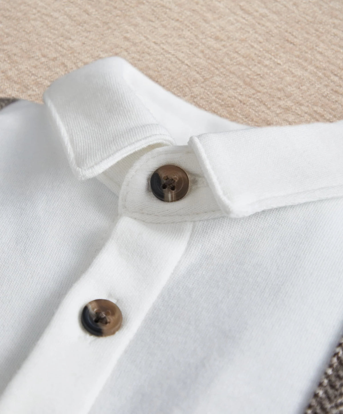 White mock-neck romper detail with brown and black buttons on collar placket