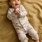 Cream long-sleeve romper with blue train pattern and turquoise snaps, baby wearing