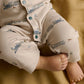 Cream long-sleeve romper with blue train print, turquoise snaps, cuffs and pant legs