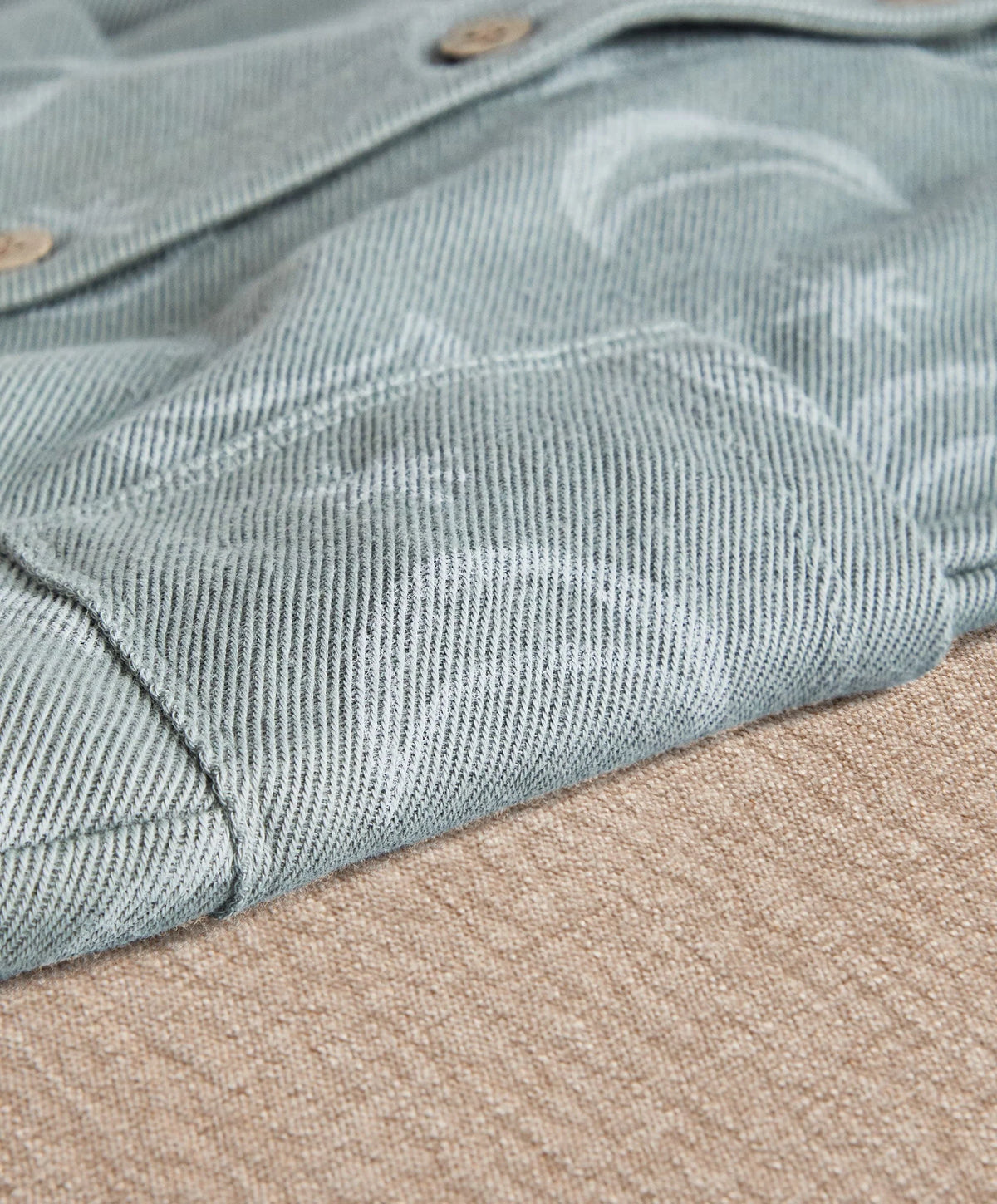 Light blue romper fabric close-up with striped texture and button details