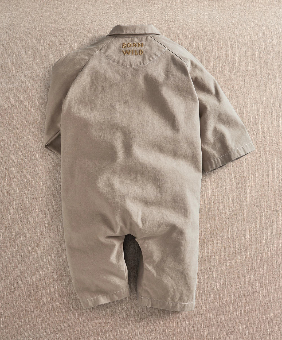Light tan oversized boiler suit romper with short sleeves and front flap pockets