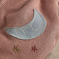 Applique trousers close-up: curved moon applique with stitched border and small stars