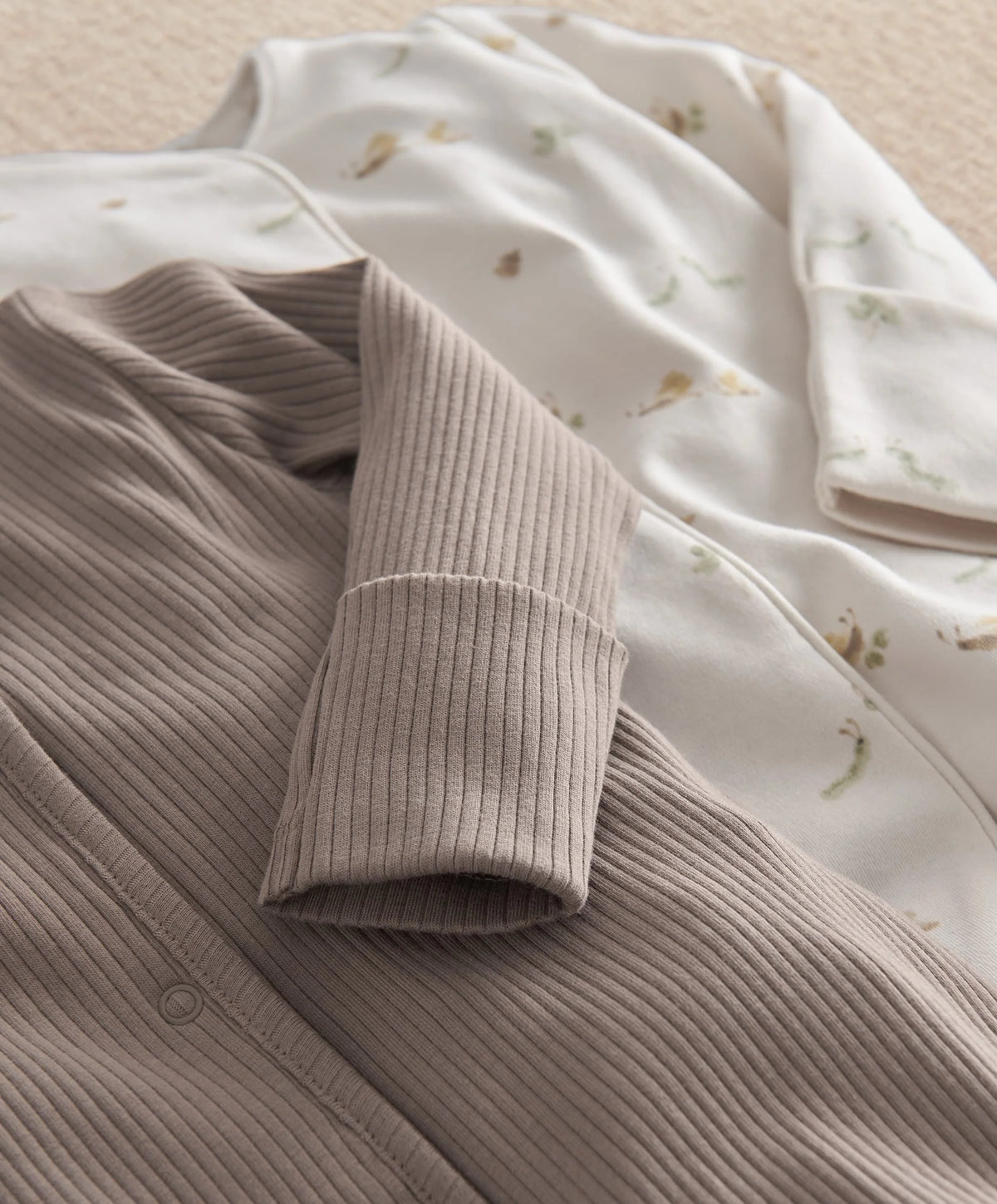 Gray ribbed button-front top with long sleeves; white printed footie with snaps