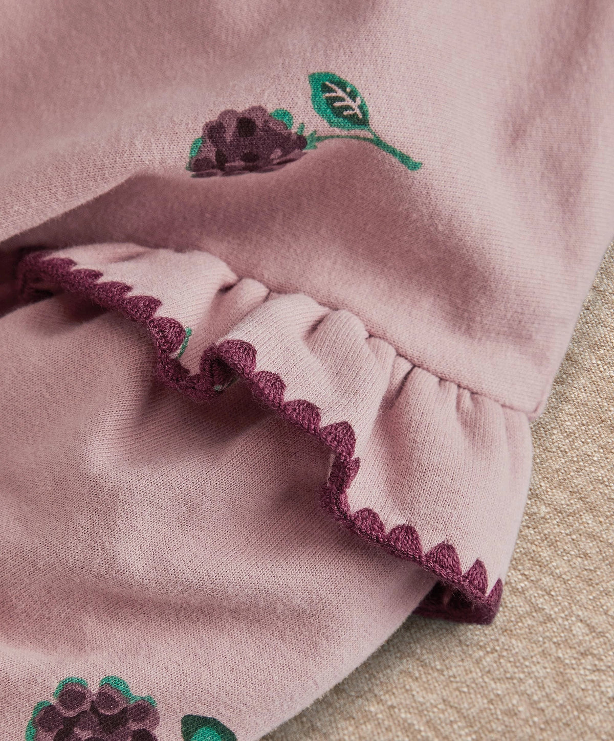 Light pink sweatshirt cuff with berry print and dark plum scalloped trim