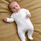 White baby all-in-one romper with duck embroidery, long sleeves and footed legs
