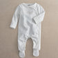 White baby long-sleeve footed all-in-one with gold embroidered “The world” text