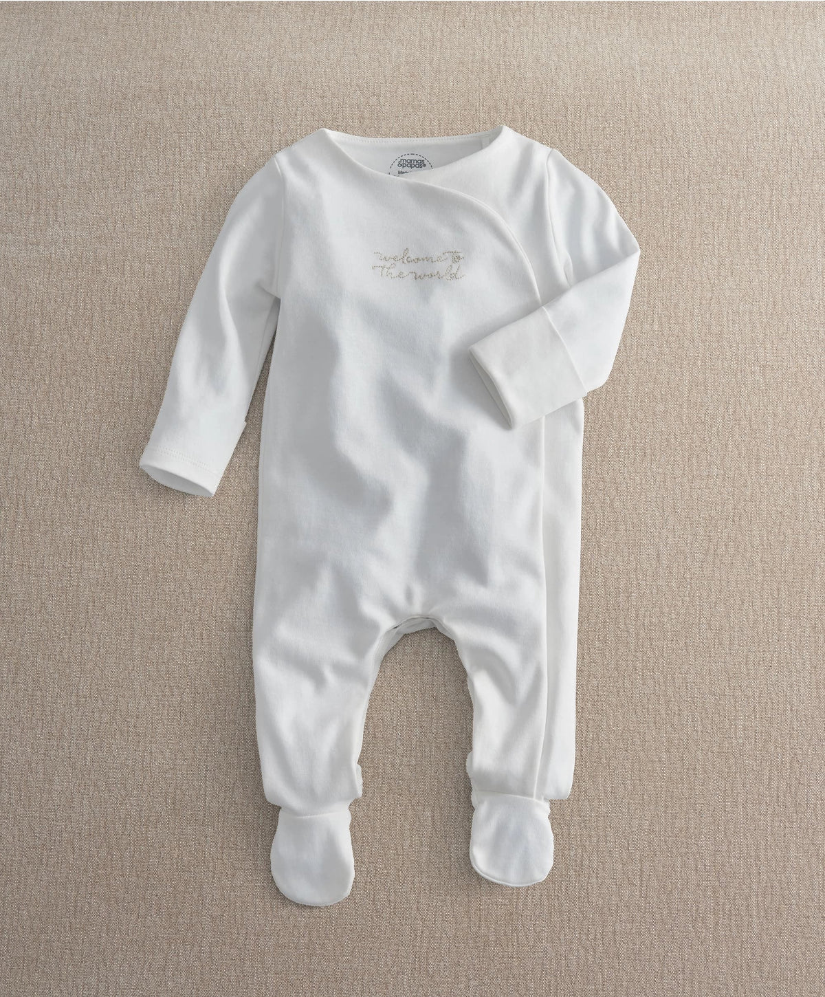 White baby long-sleeve footed all-in-one with gold embroidered “The world” text