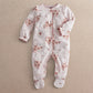 Off-white floral print all-in-one with long sleeves, footed legs, and snap closure.
