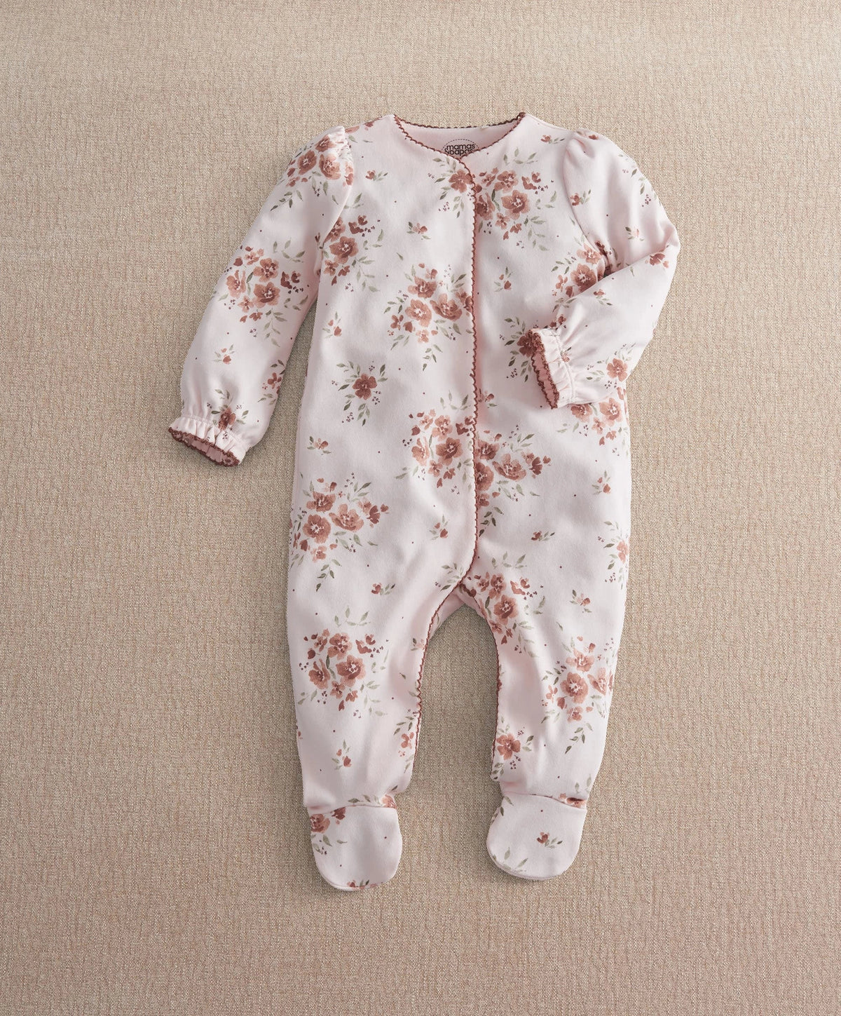 Off-white floral print all-in-one with long sleeves, footed legs, and snap closure.