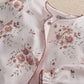 Off-white floral all-in-one close-up with snap buttons and scalloped trim.