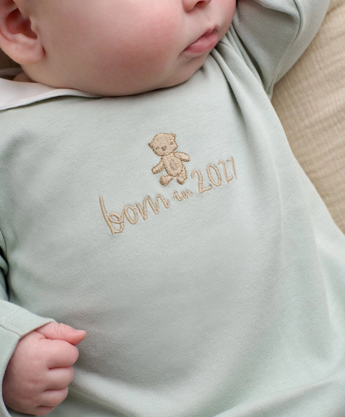 Light blue baby sleepsuit with embroidered bear and 'Born in 2027' lettering
