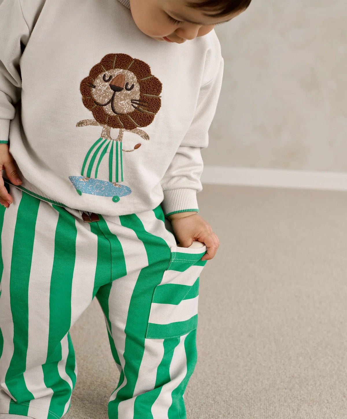 White toddler sweatshirt with lion face applique, teal ribbed neckline and cuffs