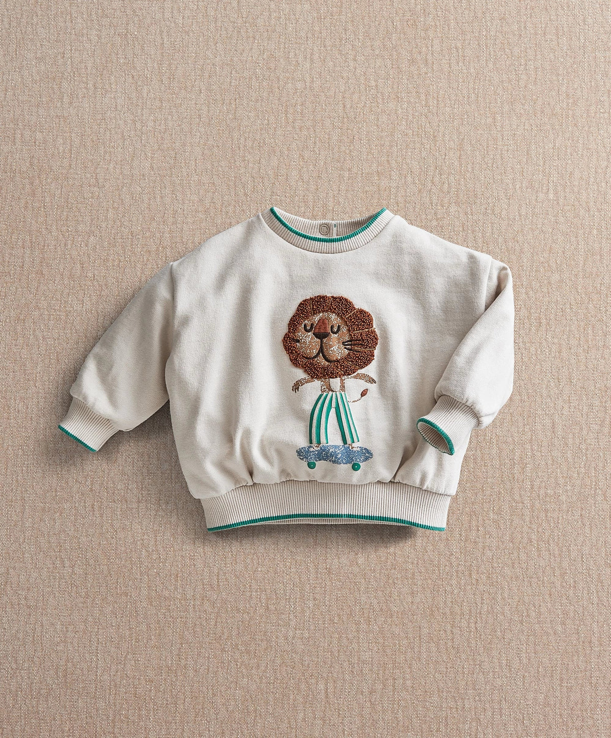 White toddler sweatshirt with lion face applique, teal-trim ribbed cuffs and hem