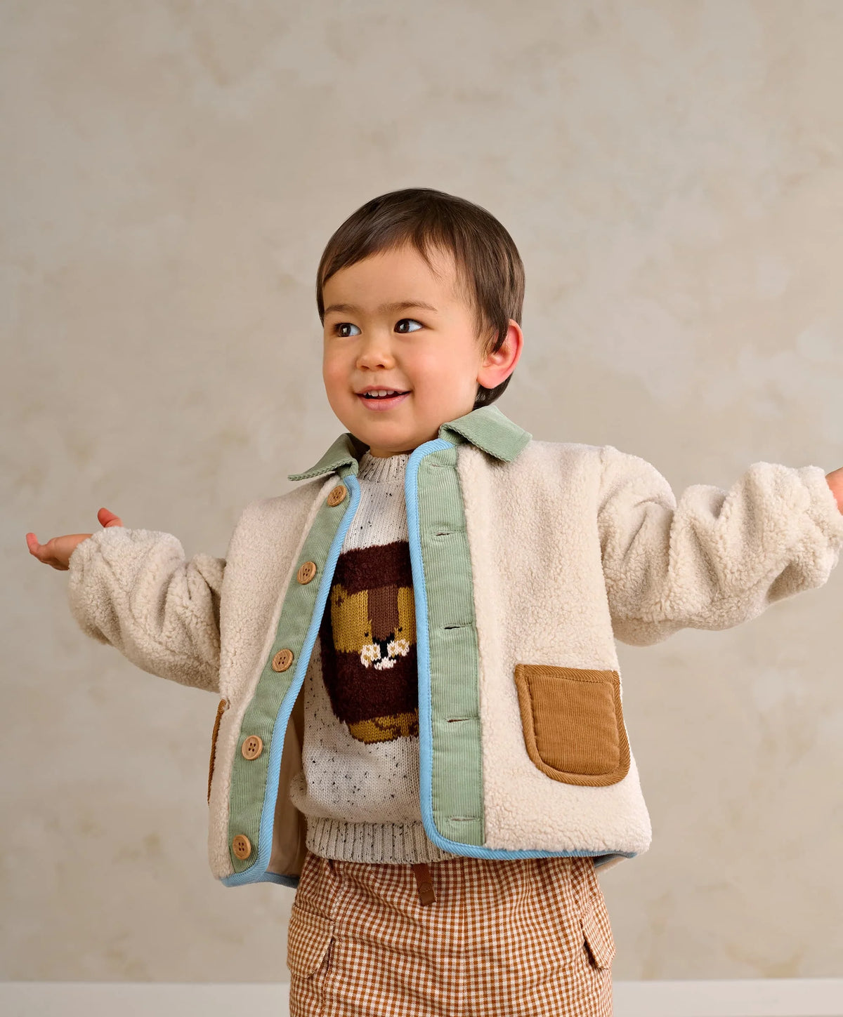 Cream borg jacket with mint lining, blue trim, tan pockets, and wooden button front