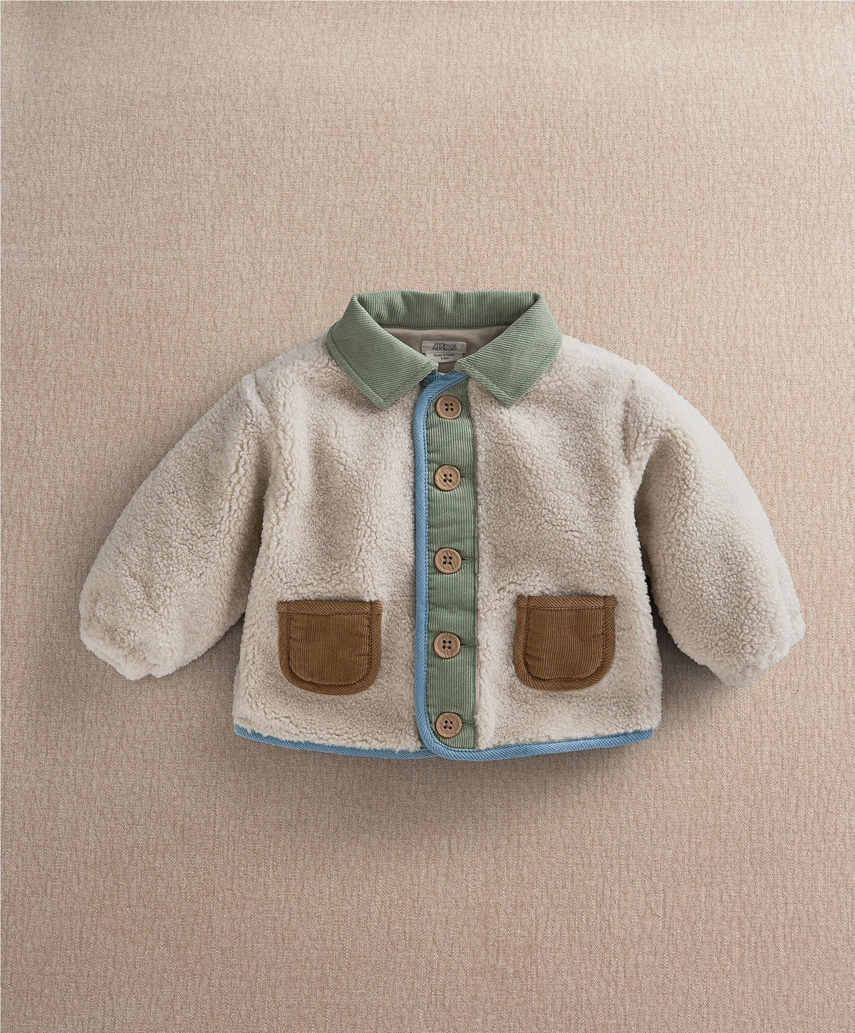 Cream borg jacket with mint collar, blue button placket, and tan front pockets