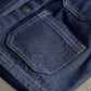 Dark blue denim jacket close-up: chest pocket with contrast topstitching and buttons