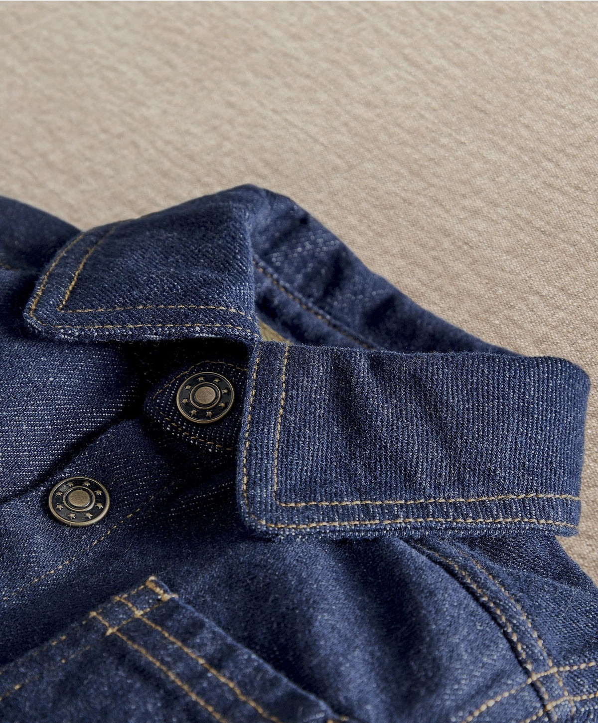 Dark blue denim jacket close-up: button placket and adjustable cuff with stitching