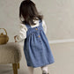 Blue denim pinafore dress over white long-sleeve bodysuit with small heart print