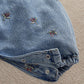 Light blue denim dungaree leg with snap buttons at cuffs and embroidered bow detail