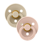 Two round latex baby pacifiers, blush pink and vanilla beige with gold accents