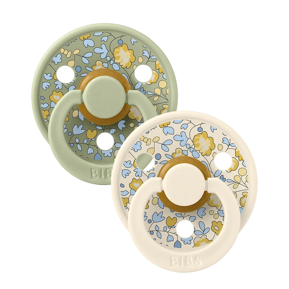 Two sage-mixed floral latex baby pacifiers, round shield with yellow ring detail