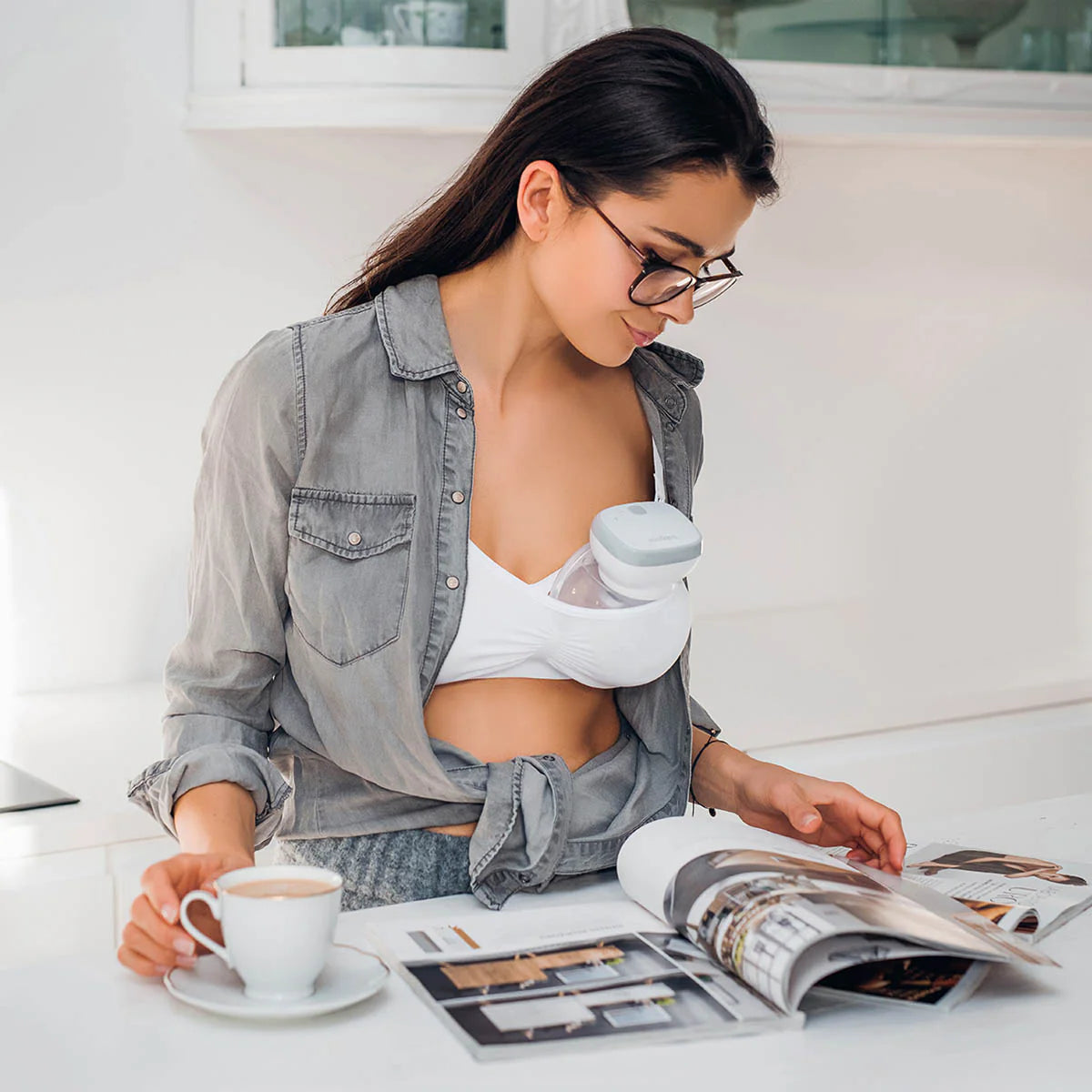 Breast pump spare parts kit in use under white nursing bra, pump cup at chest
