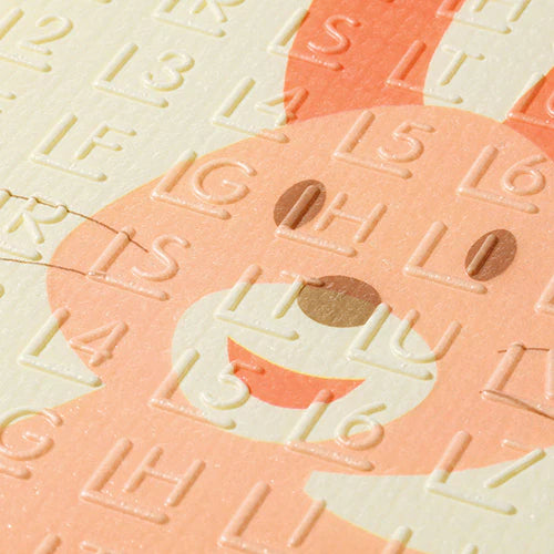 Embossed letters and numbers on foam play mat, pastel peach and cream.