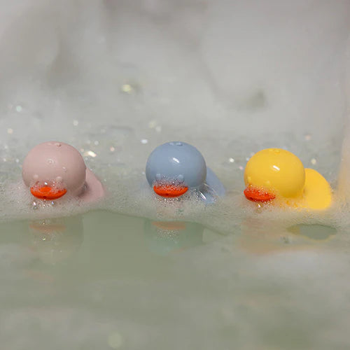 Silicone bath duck toys in bath water with bubbles and droplets