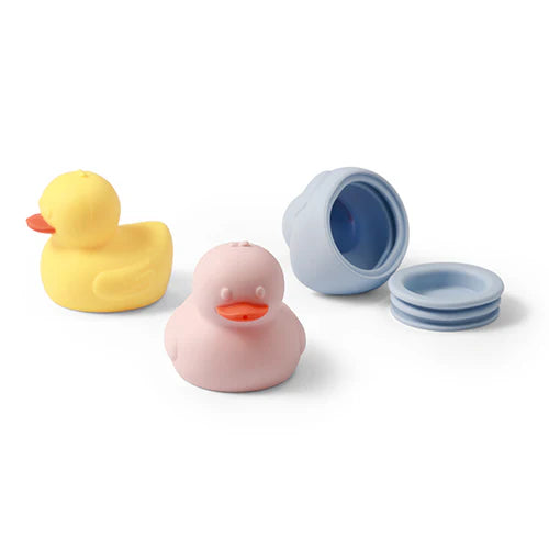 Set of three silicone bath duck toys: yellow, pink, and blue with blue cup