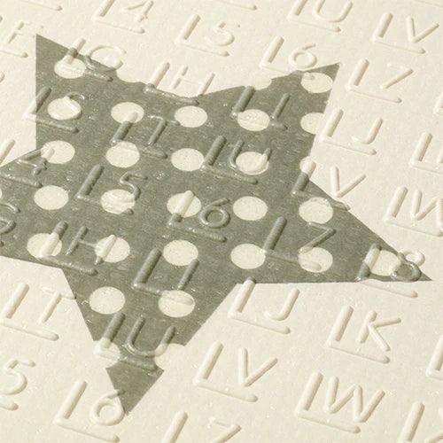 Foam play mat surface detail with raised dots and bars, pale cream with dark gray.