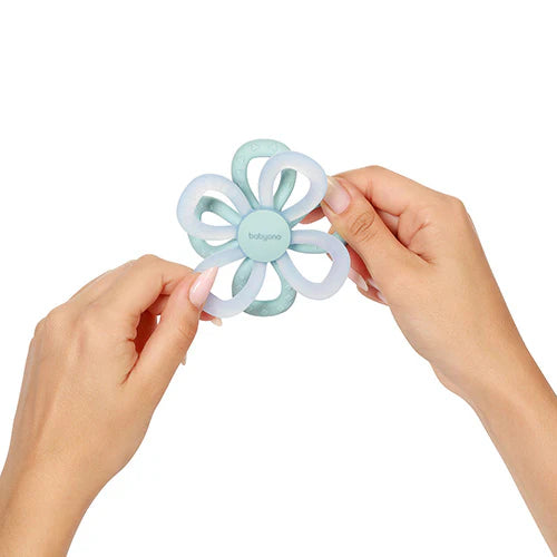 Silicone flower teether in light blue with ringed petals, held in hands