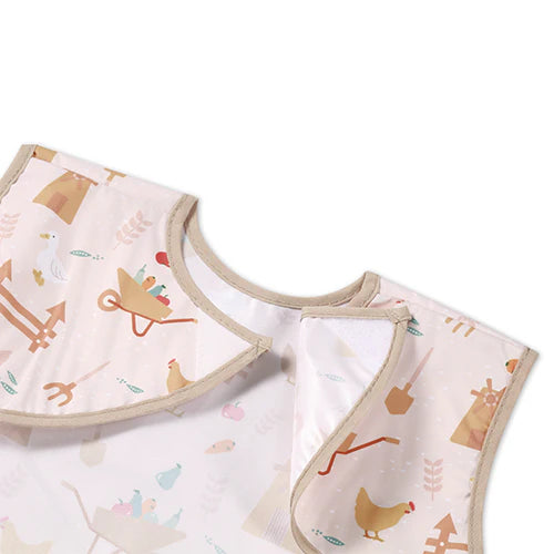 Light pink apron with farm icons, rounded neck and front pocket detail