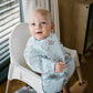 Light blue long-sleeve baby bib with airplane pattern, worn on infant