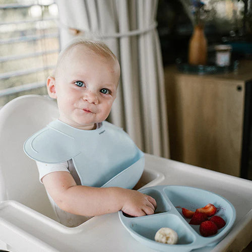 Blue silicone bib on baby, front pocket for mealtime mess