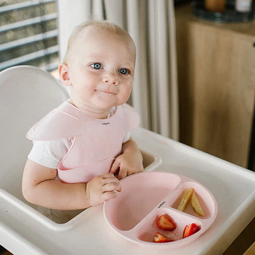 Pink silicone bib on baby in highchair, front bib and neck opening visible