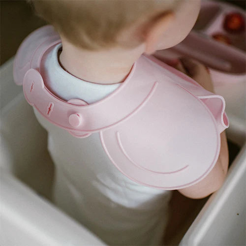 Pink silicone bib close-up, adjustable neck lock and curved front pocket details