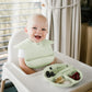 Mint silicone baby bib with adjustable lock, seated baby with feeding tray