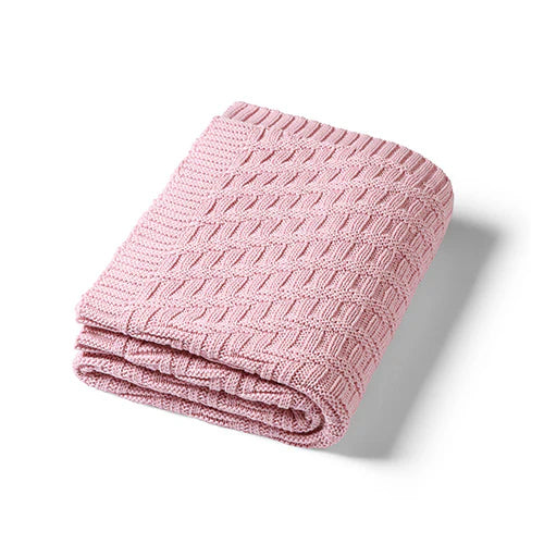 Pink knitted cotton blanket, folded with textured chevron knit and ribbed border
