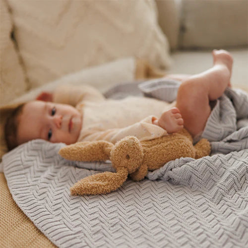 Grey cotton knitted blanket with chevron pattern wrapped around a sleeping child