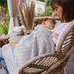 Grey cotton knitted blanket with chevron texture draped over a child being held