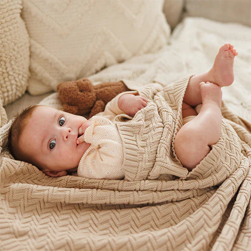 Cotton knitted blanket in beige with chevron knit texture, baby lying on blanket