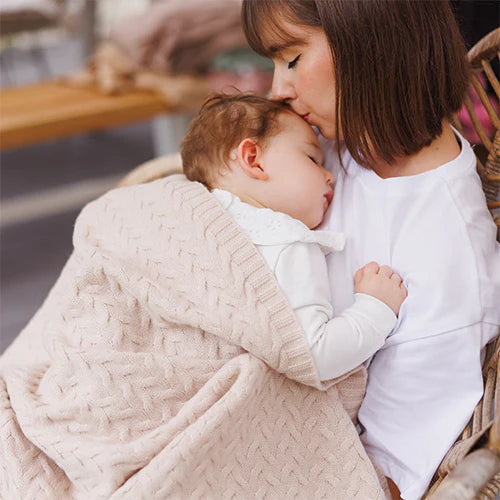 Merino wool blanket, light beige knitted wrap covering baby in arms