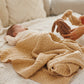Dark beige merino wool blanket covering a newborn on a bed