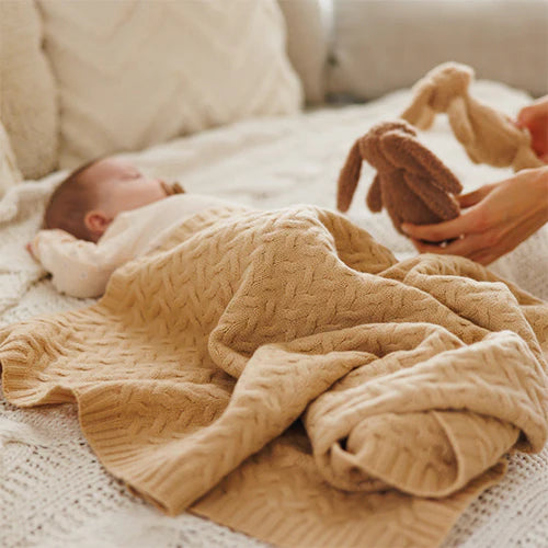 Dark beige merino wool blanket covering a newborn on a bed