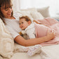 Pink blanket with flannel lining draped over baby on bed