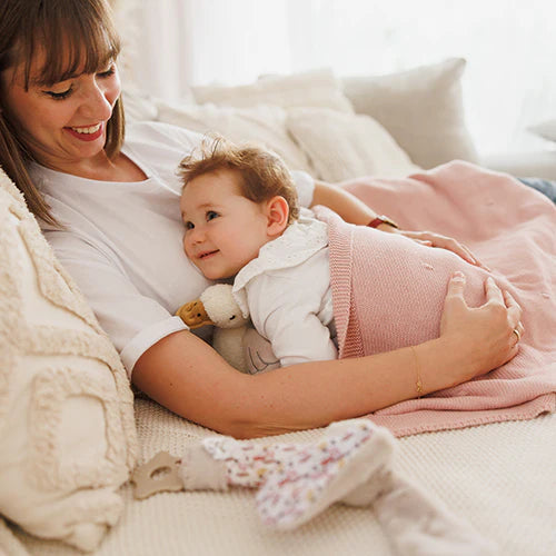 Pink blanket with flannel lining draped over baby on bed