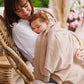 Beige flannel-lined cotton blanket draped over a person, soft knit texture visible