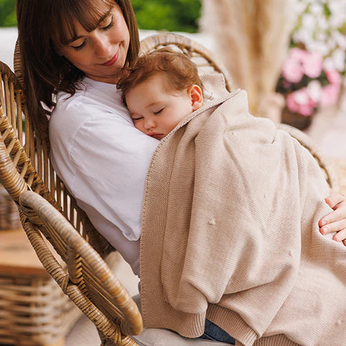 Beige flannel-lined cotton blanket draped over a person, soft knit texture visible