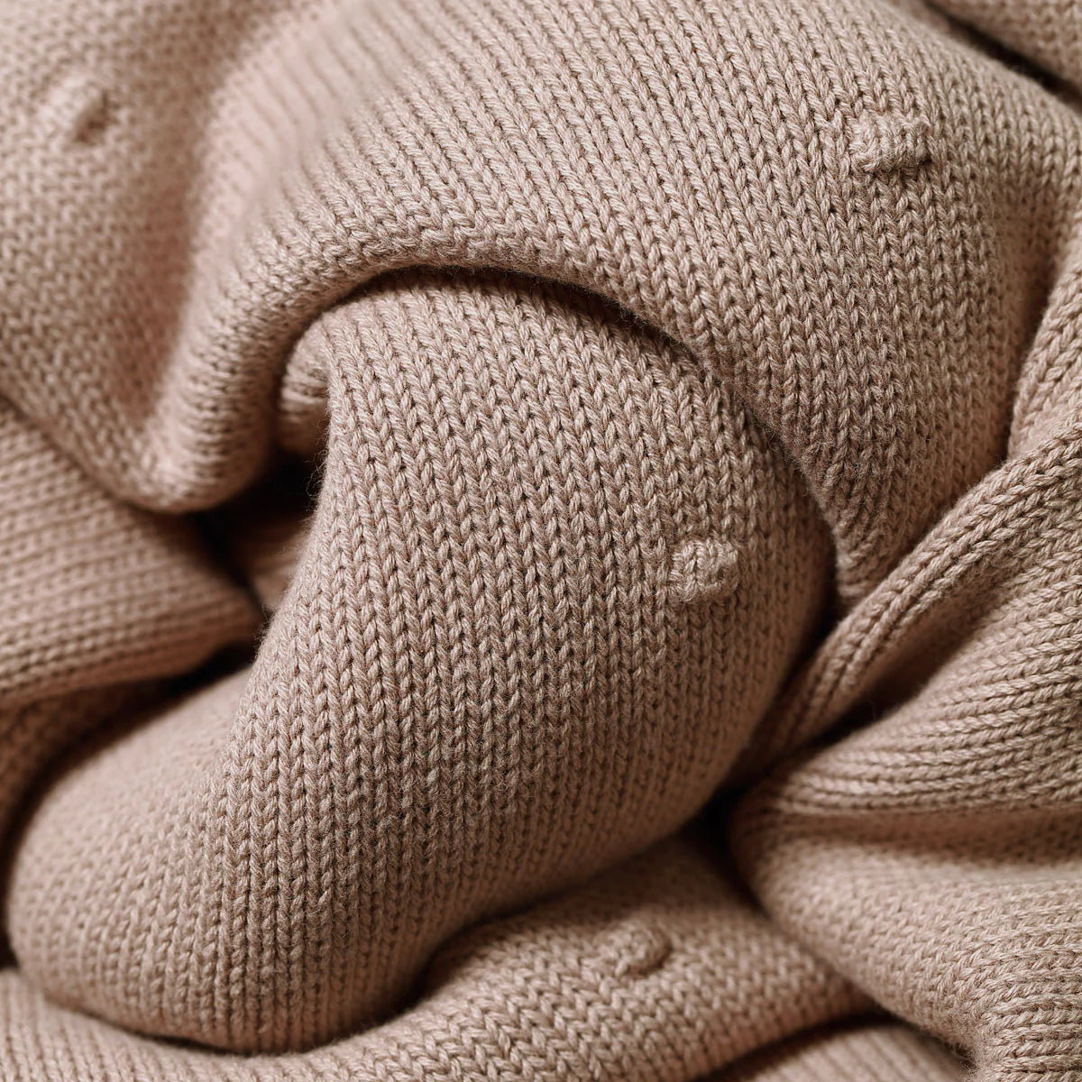 Cotton blanket with flannel lining corner close-up in tan knit fabric with rounded seam