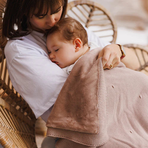 Cotton blanket with flannel lining held over baby, tan textured knit border visible